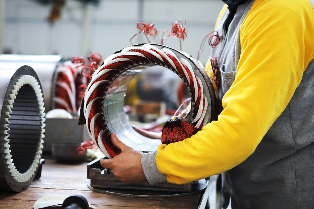 Un ouvrier assemble un stator de moteur électrique dans un atelier industriel