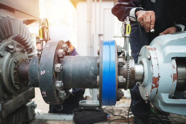 Technicien en maintenance industrielle ajuste un raccord de tuyauterie avec des outils spécialisés.